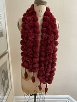 Front view of muted burgundy dyed rabbit fur scarf styled long with tassels visible at ends on dress form.
