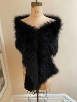 Front view of the dyed black fox fur wrap on a dress form showing the texture and lining edge visible at the bottom.