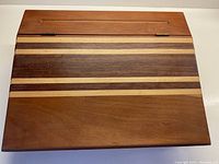 Top view of the closed wooden box showing the striped wood pattern and hinged lid.