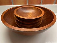 Large bowl stacked with four smaller bowls inside, showing rounded edges and smooth polished wood surface.