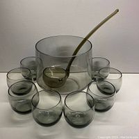 Photo showing entire punch set with large bowl in center, ladle resting inside, and eight roly-poly glasses arranged in a semicircle around bowl.