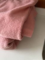 Close-up folded view of one coral pink wool blanket showing soft wool texture and fabric quality.