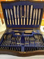 Opened oak box showing blue velvet lining, ivory-handled knives in lid and silver-plated forks and spoons in base