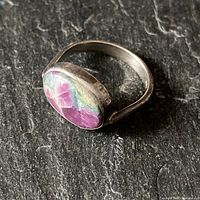 Close-up image of the sterling silver ring showing the oval pink amethyst stone with bezel setting, placed on a dark textured surface.