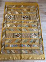 Full view of the vintage hand woven carpet showing the mustard background with geometric patterns and fringed ends.