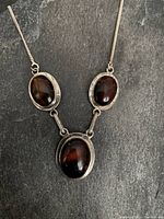 Front view of vintage sterling silver necklace with three oval tiger's eye stones showing overall design and chain.