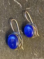 Top angle showing two blue stone earrings with sterling silver bezels and hooks
