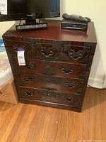 Front view of Asian-style wooden dresser with metal hardware