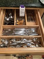 Drawer overview showing stainless flatware in wooden organizer and corn holders basket