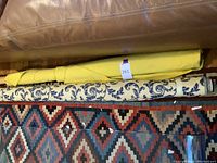 Two fabric bolts rolled on cardboard tubes: yellow solid bolt on top, blue and white damask bolt below