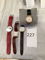Group view of all four watches on fabric background with pillow and lot number card