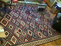 Full view of Southwestern wool rug showing geometric diamond pattern and Greek key border