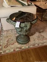 Full view of urn base supporting the round marble top on area rug