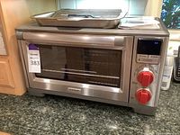 Front view of stainless steel Wolf Gourmet oven showing glass door, Wolf Gourmet badge, red knobs and digital display