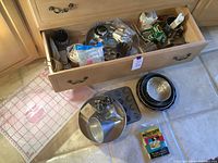 Drawer and floor shot showing measuring mat, assorted pans, cookie cutters, and other baking accessories.