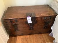 Full view of antique wooden trunk showing wood surface and metal hardware with handles.