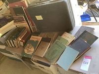 Photo showing various books spread out on a table with a black briefcase at the back.