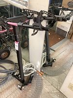 Full view of the black metal bike rack with adjustable clamps and padded arms standing upright