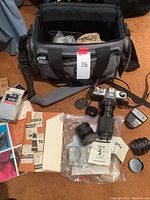 Photo showing the Pentax ME Super camera with attached Vivitar zoom lens, additional Vivitar lens, Pentax AF160 flash, lens caps, and camera case in background, alongside manuals and guides spread out on floor.