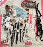 Overview of all lot items laid out on white surface including watches, bracelets, necklaces, earrings, tools and findings packs