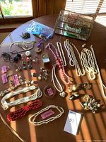 Overview of table with necklaces, earrings, rings, pendant and glass box