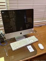 Front view of Apple iMac desktop computer with keyboard and mouse on wooden desk