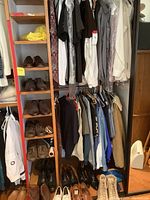 Photo showing men's clothing rack with button-down shirts in white, gray, brown, and patterned styles, leather shoes on shelves below, hanging pants below shirts.