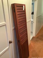 Wooden room divider folded with tag showing, leaning against wall.