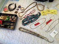 Overview of assorted necklaces, rings, brooches and tray on quilt