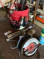 Photo of red fabric tool bucket holding hand tools and Skilsaw circular saw on table