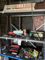 Image showing garage tools and miscellaneous items organized on metal shelves including clamp, toolboxes, wires, and various hand tools.