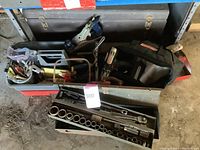 Vintage metal toolbox filled with assorted hand tools including socket sets and hand plane, ratchets visible