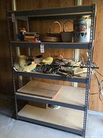 Full view of metal utility shelving unit with some items on shelves. Shelving is constructed of metal and appears stable with five shelves.