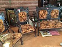 Full view of the three furniture pieces including loveseat and two chairs positioned together, showing overall design, upholstery and the dark carved wood frames.