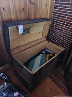 Open wooden trunk showing blankets inside and interior lid with fabric patch.