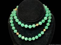 Full view of the 14K and jade bead strand necklace displayed on black velvet stand showing the double strand layout and distribution of gold beads among jade beads.