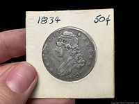 Obverse of 1834 Capped Bust Half Dollar in cardboard 2×2 holder labeled 1834 50¢