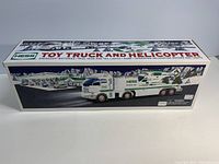 Side view of the boxed Hess 2006 toy truck and helicopter set with snowy village artwork on packaging and product image.