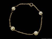Single view of pearl and gold bracelet on black background showing design and clasp.