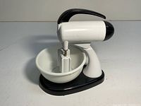Vintage plastic mixer-shaped salt and pepper shaker set, black and white, with stand and bowl.