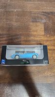 Blue Jaguar XK-120 Roadster 1/43 die-cast model in clear display box on a wooden surface, front view showing side profile.