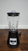 Full front view of the Oster blender, showing the glass jar and base with power cord.