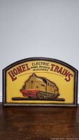 Full view of the Lionel Electric Model Trains advertising sign, showing the entire front with the raised electric train locomotive and logo text.