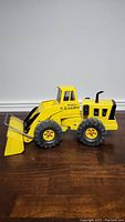 Side view of the Metal Tonka Mighty Loader showing the yellow body, cabin, black wheels, and front bucket loader arm.