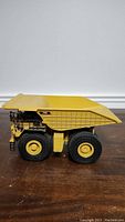 Side view of Norscot CAT 793D diecast off highway truck model showing the detailed dump bed, large tires, and cab area with CAT logo.