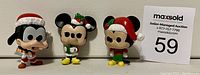 Front view of all three figures - Goofy, Minnie, and Mickey in Christmas outfits with auction card number 59.