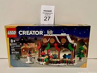 Front box image showing set name, number, recommended age, and piece count with winter market stall and minifigures in front of snowy background at night.