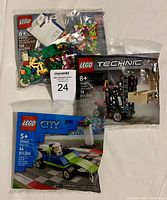 Three sealed Lego polybags including Spring Fun VIP Add-On Pack, Technic Forklift, and City Racing Vehicle on a cloth background.