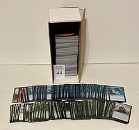 Box of over 500 Magic the Gathering cards stacked and displayed in front in two rows, mostly green and some blue cards visible.
