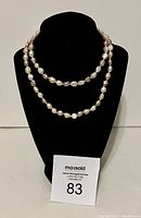 Full view of the single strand tri-coloured freshwater pearl necklace displayed on a black jewelry bust.
